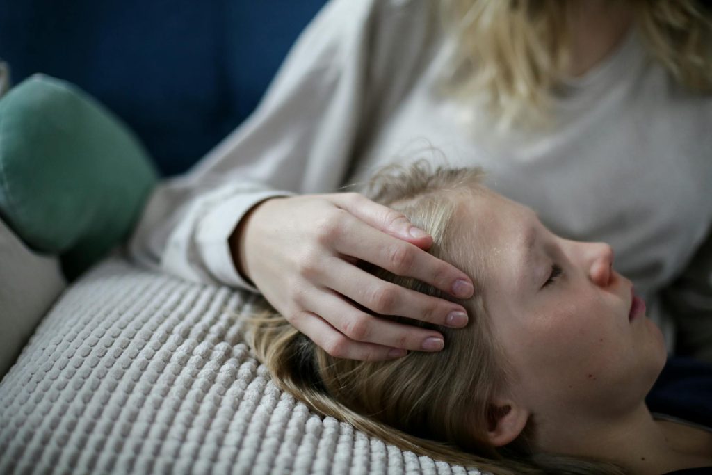 Main posée sur le front d’un enfant malade endormi sur son oreiller