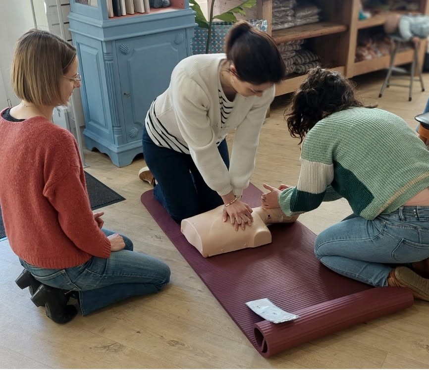 Exercice pratique de premiers secours sur un mannequin, accompagné par une formatrice